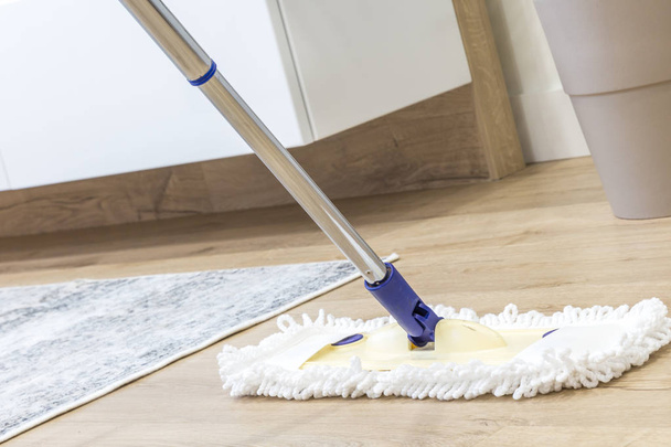 Moderna esfregona branca sendo usada para limpar um piso de madeira
 - Foto, Imagem