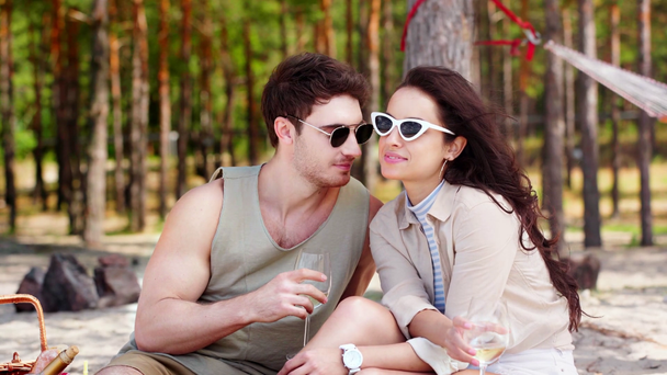 joven pareja bebiendo vino blanco, sonriendo y mirando hacia otro lado mientras descansa en la playa
 - Imágenes, Vídeo