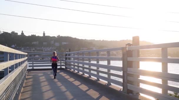 Young runner woman is running on beach at sunset, endurance workout. Slow motion. - Video, Çekim