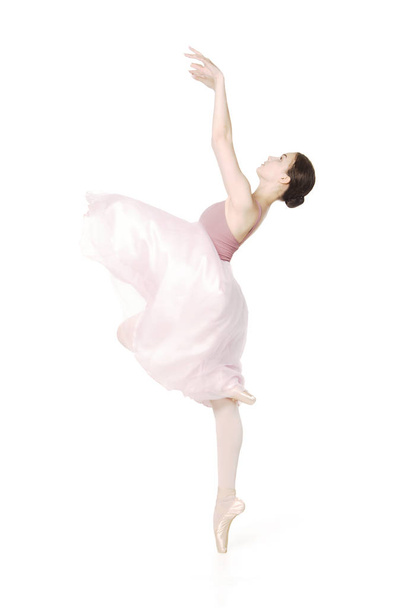 Elegant girl in a pink skirt and beige top dancing ballet. - Фото, изображение