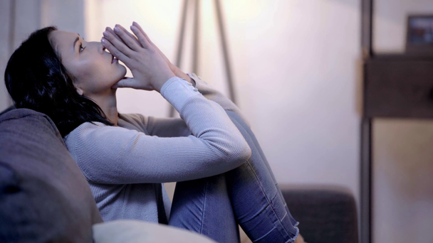 πλευρική όψη της θλιμμένα γυναίκα κάθεται στον καναπέ  - Πλάνα, βίντεο