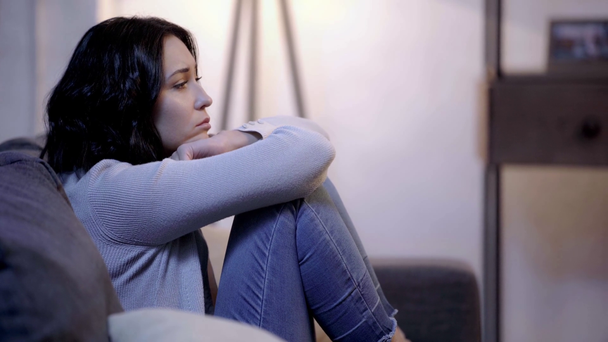 side view of sad woman sitting on sofa  - Footage, Video