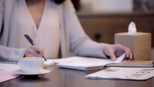 обрезанный вид женщины пьющей и пишущей в блокноте
  - Кадры, видео