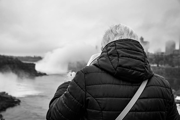 Турист с биноклем, указывающим на Ниагарский водопад
 - Фото, изображение
