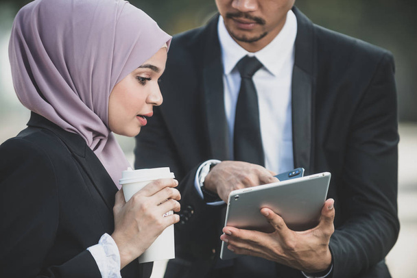 Uomo d'affari musulmano e partner donna d'affari discutono utilizzando ta
 - Foto, immagini