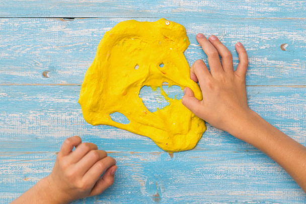 L'enfant étire la bouche de la boue jaune avec sa main droite
. - Photo, image