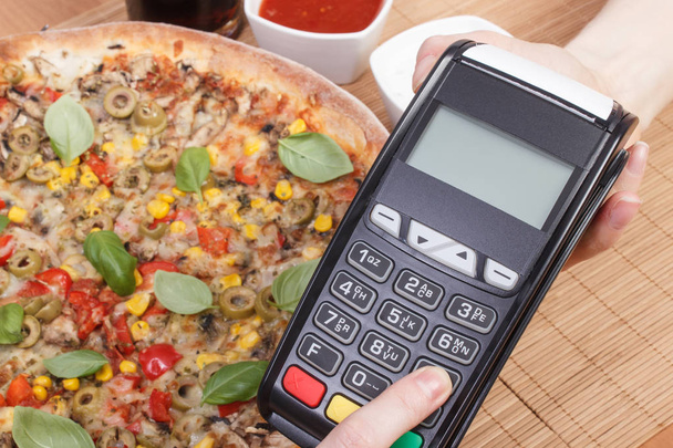 Using payment terminal for paying in restaurant, enter personal identification number, vegetarian pizza - Foto, imagen