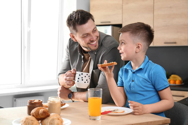 Dad and son having breakfast together in kitchen - Photo, image