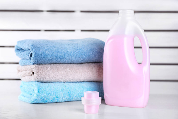 Laundry detergent and clean towels on table against blurred background - Photo, image