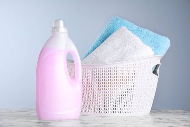 Bottle of laundry detergent and basket with towels on table - Foto, imagen