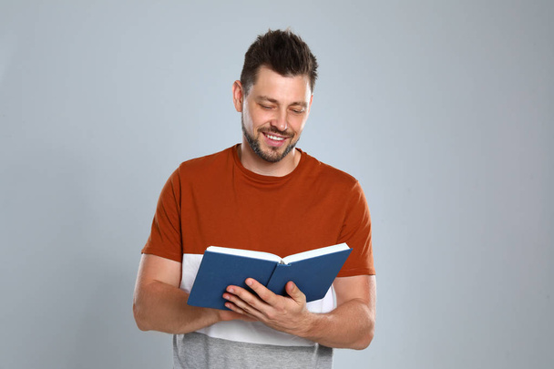 Handsome man reading book on light background - Photo, Image