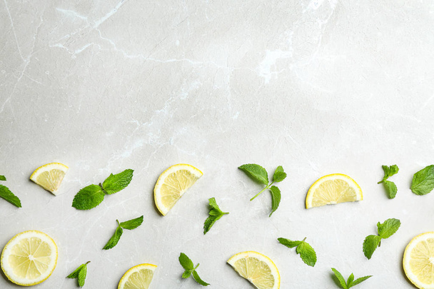 Fresh mint with sliced lemon on grey marble background, flat lay. Space for text - Foto, imagen