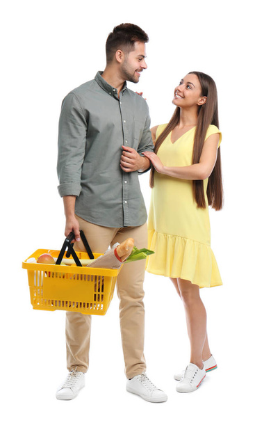 Young couple with shopping basket full of products isolated on white - Foto, Imagem