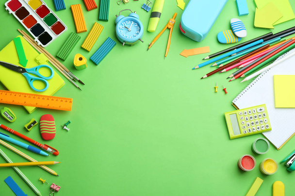 Different bright school stationery on light green background, flat lay. Space for text - 写真・画像