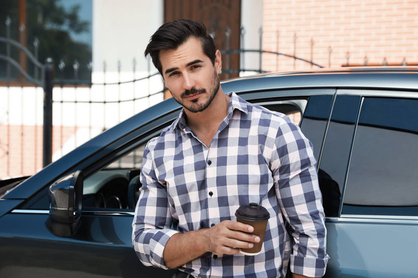Attractive young man with cup of coffee near luxury car outdoors - Photo, Image