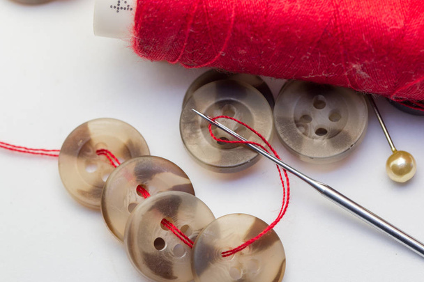 Nadel mit Faden und Knopf isoliert auf Weiß, Handarbeit und Schneiderkonzept - Nähen von Knöpfen, Nadeln und Nadeln. - Foto, Bild