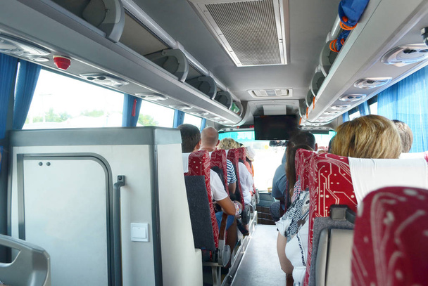 tourist trip in the bus with people, blue curtains, luggage racks - Photo, image