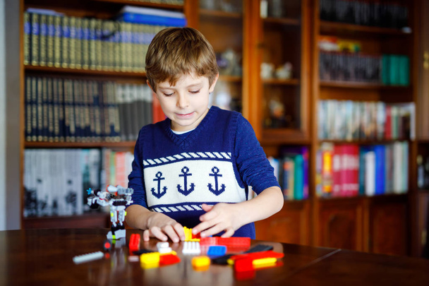 Renkli plastik bloklar çok oynayan küçük sarışın çocuk. Sevimli okul çocuk çocuk bina ve robot oluşturma ile eğlenmek. Yaratıcı eğlence modern teknik ve robotik. - Fotoğraf, Görsel