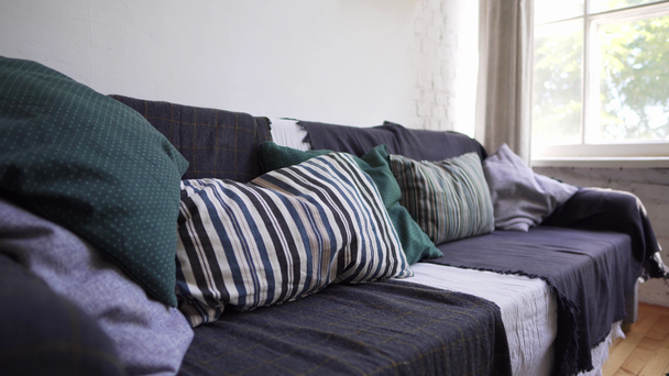 Hygge or Lagom concept - a cozy sofa with a lot of pillows and blankets with bedspreads - Footage, Video