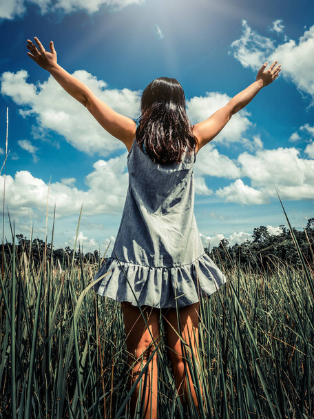 Молодая женщина на зеленой траве распростирает руки к небу
. - Фото, изображение
