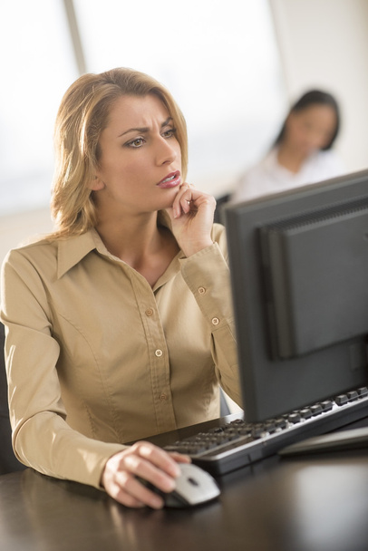 Verwirrte Geschäftsfrau benutzt Computer am Schreibtisch im Büro - Foto, Bild