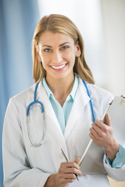 Portrait Of Confident Doctor Holding Clipboard In Clinic - Zdjęcie, obraz