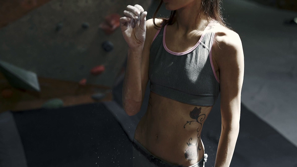 σιλουέτα της ταιριάζει λεπτή γυναίκα ορειβάτη χέρια και την ανατίναξη κιμωλία από τα δάχτυλα πριν από την ανάβαση σε εσωτερικό γυμναστήριο αναρρίχησης. αθλητική γυναίκα με καλούς κοιλιακούς και γυμνό κορμό να ετοιμάζεται να - Πλάνα, βίντεο