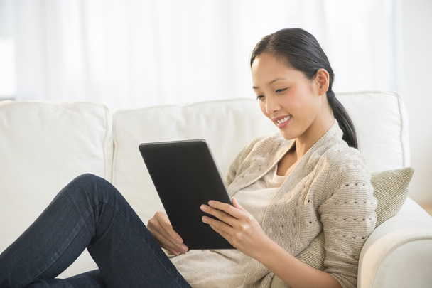 Beautiful Woman Using Digital Tablet While Relaxing On Sofa - Photo, Image