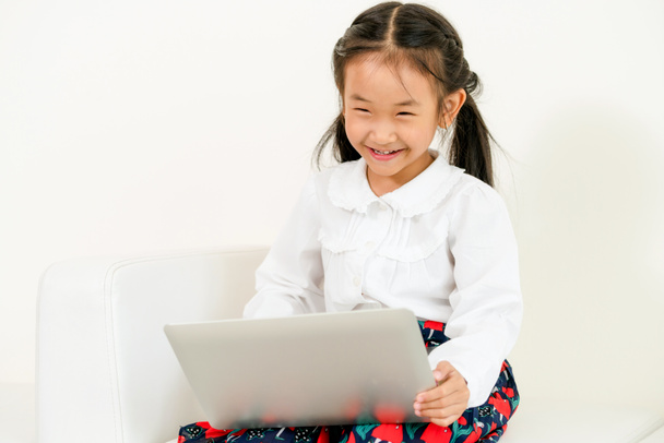 Pieni lapsi käyttää kannettavaa tietokonetta valkoisella sohvalla
. - Valokuva, kuva