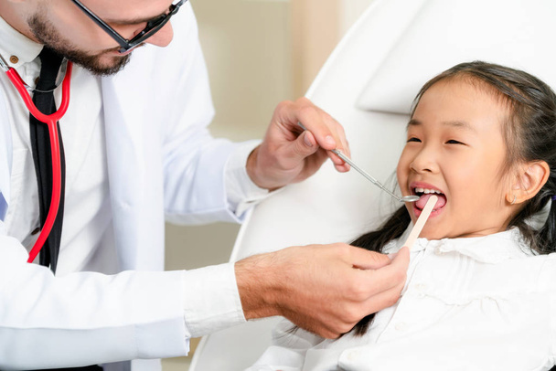 Οδοντίατρος που εξετάζει τα παιδικά δόντια στην οδοντιατρική κλινική. - Φωτογραφία, εικόνα