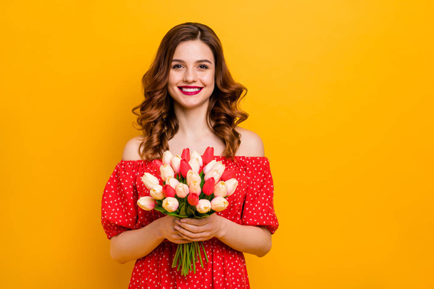 Beautiful foxy lady holding arms fresh tulips bunch wear off-shoulders dress isolated bright yellow background - Foto, Imagem