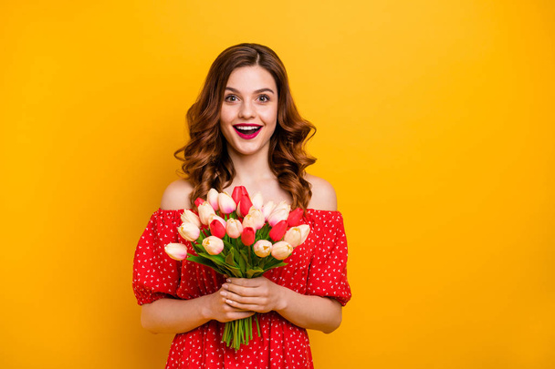 Beautiful foxy lady holding arms fresh tulips bunch wear off-shoulders dress isolated bright yellow background - Photo, image