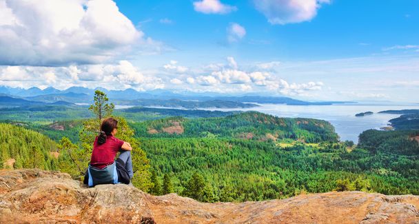 女性は岩の上に座って、バンクーバー島、ブリティッシュ コロンビア州、カナダの美しい眺めを楽しむ - 写真・画像