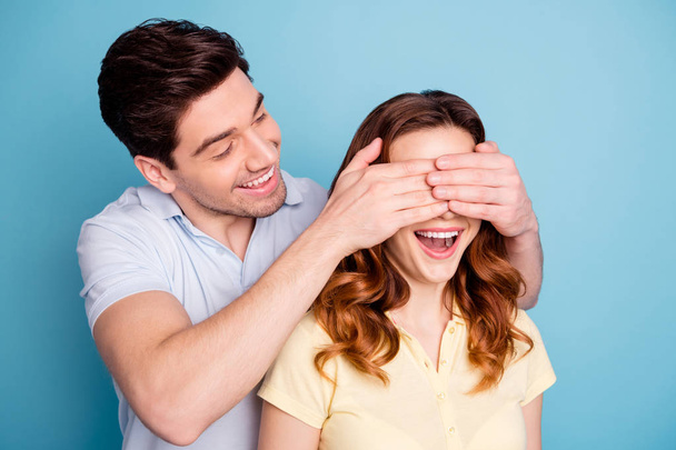 Photo of pair excited bonding romance moment hide eyes do not look guess who wear casual t-shirts isolated blue background - Foto, Imagen