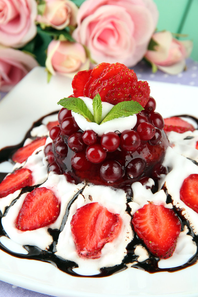 Tasty jelly dessert with fresh berries, on pink roses background - Фото, зображення