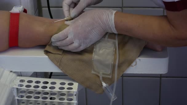 Der Spender spendet Blut in der Klinik. Spender spendet Blut, Krankenschwester sticht Nadel in Spendervene. das Pumpen von Blut aus einer Vene in eine Vakuumröhre zur Blutentnahme. Nahaufnahme - Filmmaterial, Video