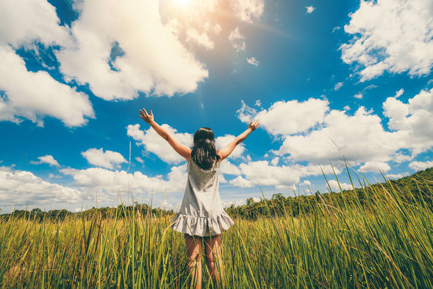 Молода жінка на зеленій траві розтягує руки на небо
. - Фото, зображення