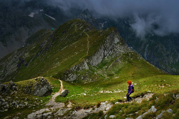 Caucasian woman hiker with backpack walking a trail in rocky mountains - Fotografie, Obrázek