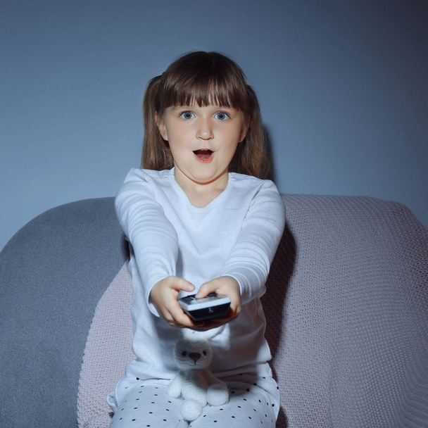 Эмоциональная маленькая девочка смотрит телевизор ночью
 - Фото, изображение