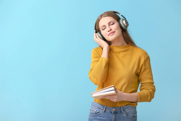 Young woman listening to audiobook on color background - Foto, Bild