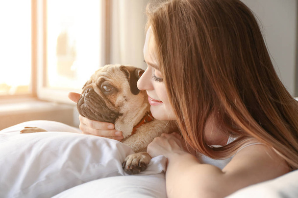 Reggel a gyönyörű fiatal nő aranyos mopszli kutya hálószoba - Fotó, kép