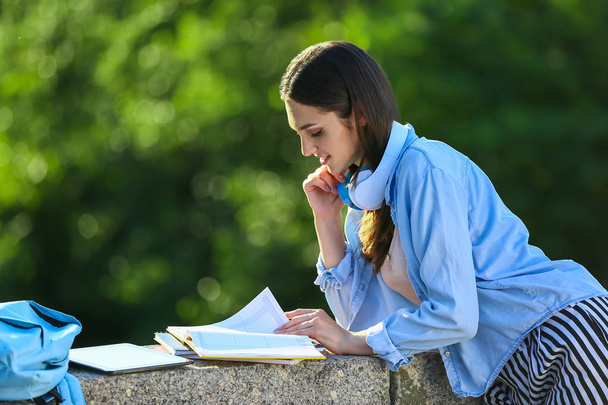 Hermosa estudiante femenina con auriculares al aire libre
 - Foto, imagen