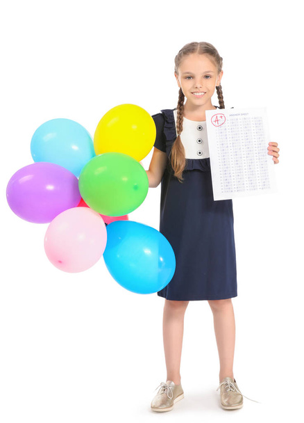 Ευτυχισμένο κορίτσι με το φύλλο απαντήσεων για το σχολείο τεστ και μπαλόνια σε λευκό φόντο - Φωτογραφία, εικόνα