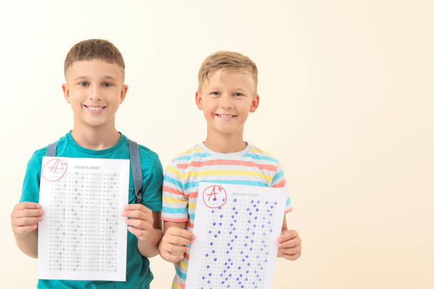 Boldog fiúk válaszlapokat iskolai teszt világos háttér - Fotó, kép