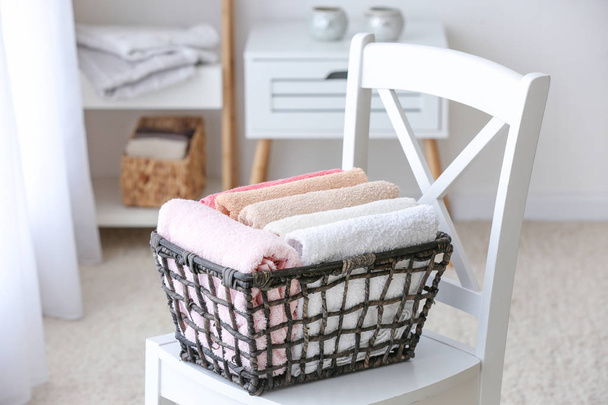 Cesta com toalhas macias limpas na cadeira no banheiro
 - Foto, Imagem