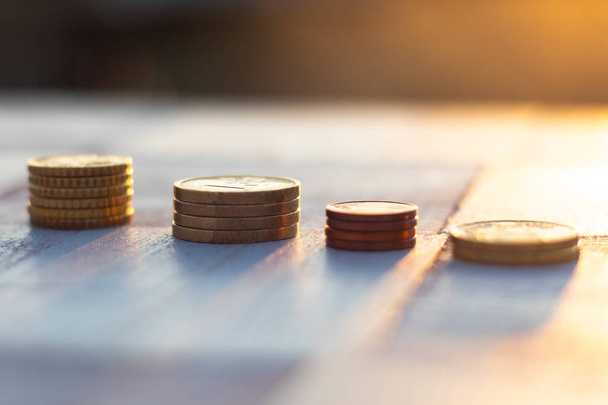 Pilhas de moedas em cima da mesa sobre o belo fundo do pôr-do-sol, crescimento da economia e conceito de estratégia
 - Foto, Imagem