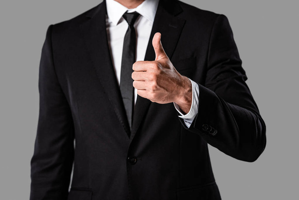 partial view of businessman in black suit showing thumb up isolated on grey - Fotografie, Obrázek