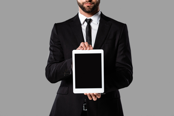 osittainen näkymä liikemies musta puku näyttää digitaalinen tabletti tyhjä näyttö eristetty harmaa
 - Valokuva, kuva