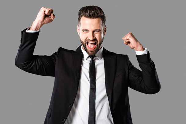 glücklicher Geschäftsmann im schwarzen Anzug zeigt Ja-Geste isoliert auf grau - Foto, Bild