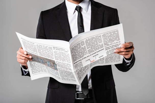 częściowy widok biznesmen w kolorze czarnym z gazetą wyizolowaną na szaro - Zdjęcie, obraz